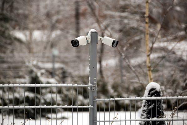 Two cameras atop fence in winter time